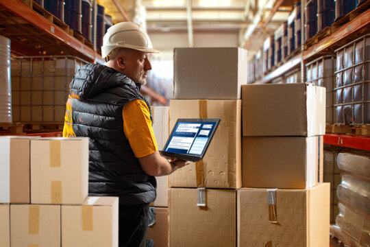 Warehouse Manager Conducting Inventory with Digital Tablet Among Cardboard Boxes