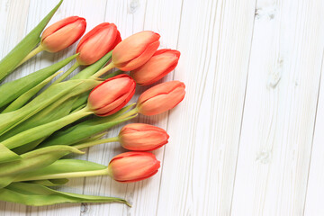 Bouquet of pink tulips on a light wooden background, top view. Flowers for banners and cards. Bouquet of flowers with selective focus. Tulips on a wooden table, background with copy space