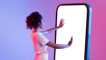 Smiling woman interacting with giant smartphone on colored backdrop