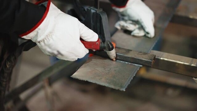 Process of heating metal surface and then cutting with oxy fuel torch, welder in protective gloves working with steel in workshop, worker cutting metal plate and frame, welding and grinding creating