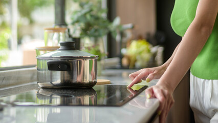 Asian woman cooking and smelling tasting soup in a pot in the kitchen table at home.