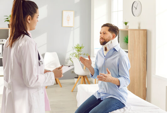 Young man injured after accident and wearing neck brace sitting on the couch in medical clinic and talking to female doctor traumatologist. Neck injury, medicine and trauma treatment concept