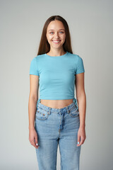 Portrait of smiling young woman in blue T-shirt on gray background