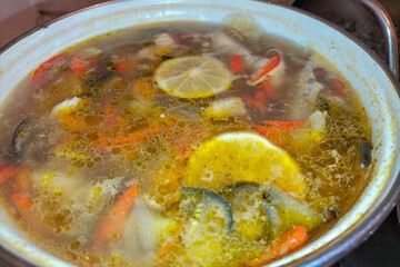 A beautiful and delicious-looking soup made of various vegetables, carrots, potatoes with the addition of lemon and amber-colored fat droplets floating on the surface of the broth. Culinary delights