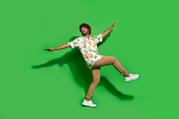 Fototapeta na wymiar Full length photo of carefree funky latin guy dressed print shirt having fun dancing empty space isolated green color background