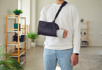 Man bravely standing despite a broken arm with fracture in the bone encased in a protective cast...