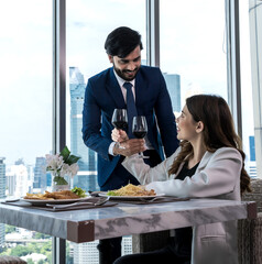 Indian man and young Asian woman drinking wine on dinner dating at rooftop restaurant