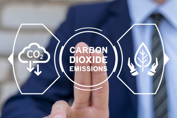 Businessman using virtual touch screen presses inscription: CARBON DIOXIDE EMISSIONS. Concept of reducing CO2 emissions to stop climate change. Reduce Carbon Dioxide Emissions to Limit Global Warming.