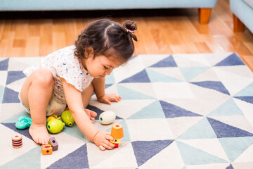 Linda bebe de 2 años sentada jugando con bloques en su habitación