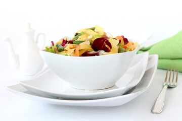 Vegan salad with mango, cashews, carrots and radicchio served on the table. Light background. Healthly food.
