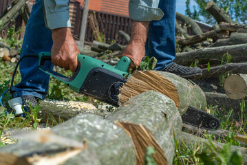 Cord Chainsaw. Close-up of woodcutter sawing chain saw in motion, sawdust fly to sides. Chainsaw in...