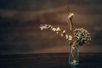 Close up and selective focus dry flowers in vase on wooden table in dining room or restaurant,still life concept.
