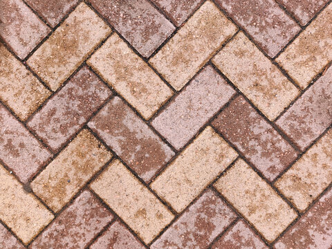Herringbone brick sidewalk pattern of pavement tiles on rainy day background texture. Wet sidewalk pathway surface. Patio pavement. Exterior design element. Geometric diagonal zigzag tile pattern.