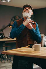 Portrait d'un hipster barbier avec une belle barbe en train de se raser avec une tondeuse dans un atelier