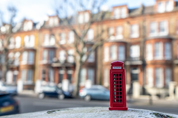 London residential street of terraced townhouses with miniature red phone box in foreground