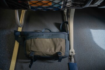 Passenger put a bag under the aircraft seat for safety flight.