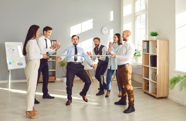 Fototapeta premium Group of happy funny young business people company employees having fun organizing competitions between coworkers in office with a stick. Teamwork, corporate team building and success concept.