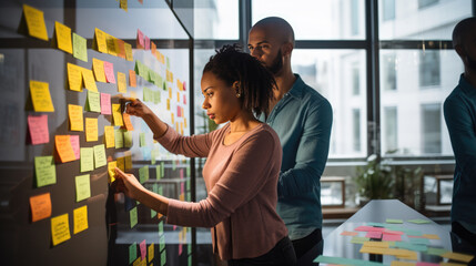 A professional team engaged in a brainstorming session, using colorful sticky notes on a glass wall to organize their ideas and strategies. - obrazy, fototapety, plakaty