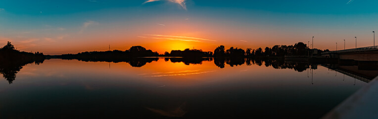 High resolution stitched summer sunset panorama with reflections near Plattling, Isar, Bavaria,...