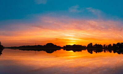 High resolution stitched summer sunset panorama with reflections near Plattling, Isar, Bavaria,...
