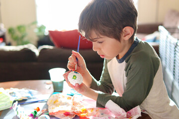 Child painting easter eggs at home