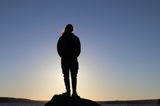 A silhouette man staring backlit by the sun