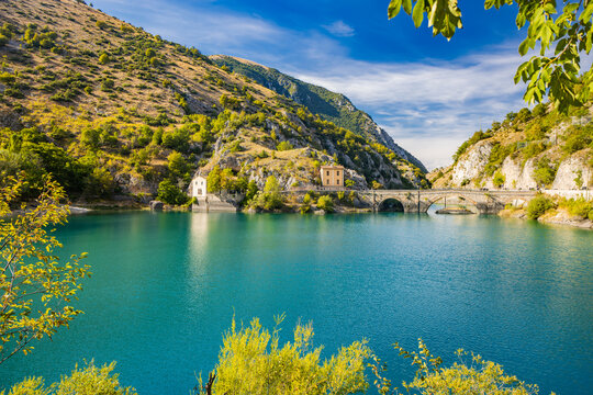 Lake San Domenico, in the Sagittario Gorges, in Abruzzo, L'Aquila, Italy. The small hermitage with the stone bridge. The turquoise color of the water. The glow of the sun, flare at sunset.