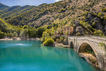 Lake San Domenico, in the Sagittario Gorges, in Abruzzo, L'Aquila, Italy. The small hermitage with the stone bridge. The turquoise color of the water. The glow of the sun, flare at sunset.