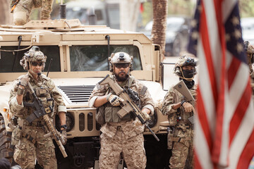 Portrait of soldiers in camouflage uniforms hold weapons in front of a military communication vehicle