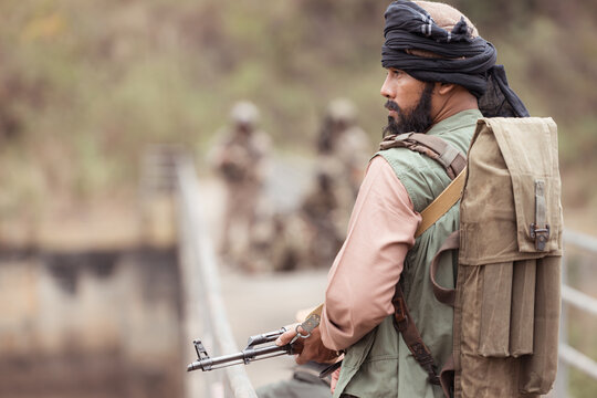 A group of Allied soldiers in camouflage wearing weapons clash with group of taliban soldiers