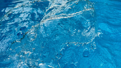 Background dynamic splash of clear water creating swirling wave in blue water with droplets...