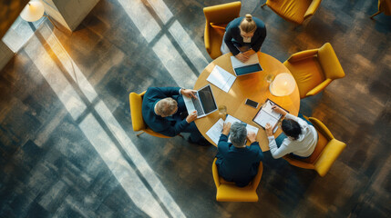 Aerial view of a professional meeting with four individuals around a round table - obrazy, fototapety, plakaty