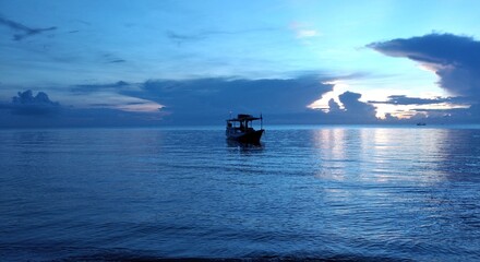 Obraz premium Fishing boat in the sea at sunset