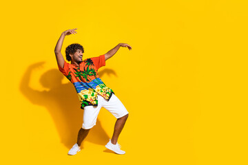 Full length photo of optimistic guy wear hawaii print shirt hold arms up look at discount empty space isolated on yellow color background
