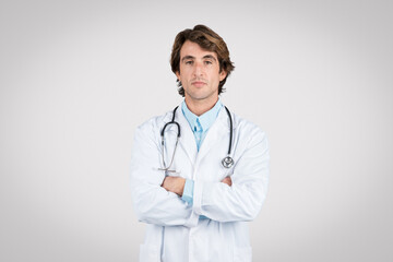 Fototapeta premium Confident male doctor with stethoscope standing with arms crossed