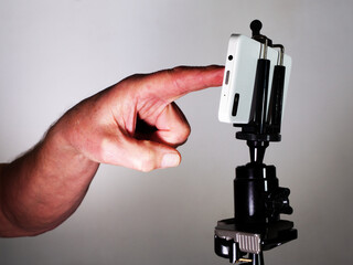 Closeup of a man’s hand touching a screen to take a picture or photo with a mobile or cell phone,...