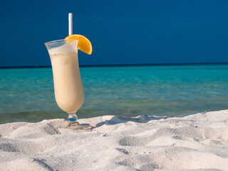 Un cocktail de fruit posée sur une plage de sable blanc paradisiaque tropicale.