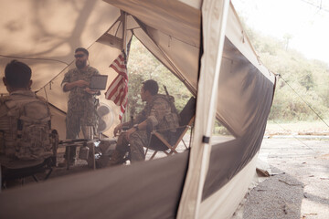Group of soldiers in camouflage uniforms hold weapons in a field tent, Plan and prepare for combat training.