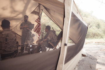 Group of soldiers in camouflage uniforms hold weapons in a field tent, Plan and prepare for combat...