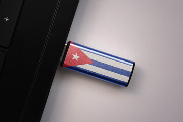 usb flash drive in notebook computer with the national flag of cuba on gray background.