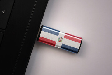 usb flash drive in notebook computer with the national flag of dominican republic on gray background.