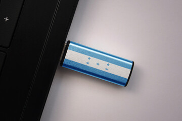 usb flash drive in notebook computer with the national flag of honduras on gray background.