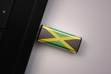 usb flash drive in notebook computer with the national flag of jamaica on gray background.