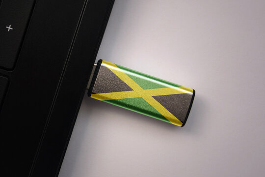 usb flash drive in notebook computer with the national flag of jamaica on gray background.
