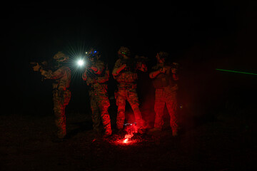Group of soldiers in camouflage uniforms hold weapons with patrol missions at night
