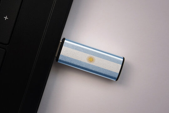 usb flash drive in notebook computer with the national flag of argentina on gray background.