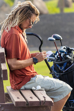 Unique golfer with dreadlocks checking score during game