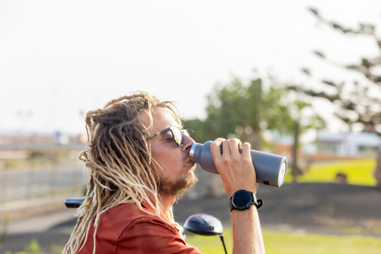 Unique golfer with dreadlocks enjoying a water break
