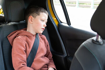 Young boy wearing seatbelt in car looking away