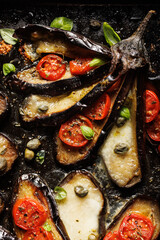 Close up of roasted eggplant in the fan shape stuffed with cherry tomatoes and mozzarella cheese sprinkle herbs on a d black background - 757415437